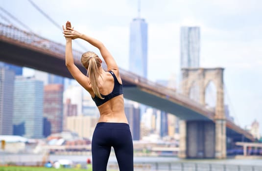 Woman, stretching back for workout in city for fitness or exercise, physical health and stress relief. Girl active to warm up muscle, cardio and training for sports runner or athlete in New York.