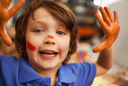 Happy boy, portrait and hands with face paint for artwork, craft or creativity at elementary school. Little male person, child or kid with smile for colorful art, youth or early childhood development