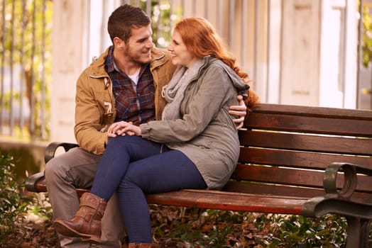 Couple, love and sitting with hug at park in cold weather or winter, together and smile in London. Relationship, commitment and bonding for romance with soulmate, care and happiness on holiday.