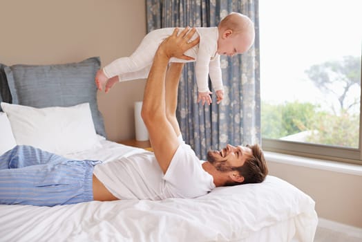Happy, laughing and baby with father on bed relaxing, playing and bonding together at home. Smile, love and young dad holding girl child, infant or kid in bedroom or nursery at family house