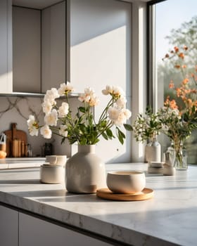 Flowers on marble table of modern kitchen interior. Cozy fashionable kitchen decor. White aesthetic kitchen interior details and decor.