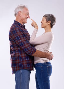 Senior, couple and happy hug in studio together, smile and retired people in elderly love relationship. Pointing, female person with man on white background, affection on mockup space with joy.