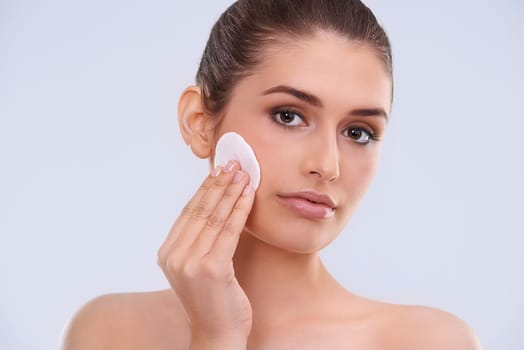 Portrait, woman and cotton pad for makeup removal from skin, cosmetics and beauty product on white background. Skincare routine, cleanse and wipe face, dermatology and facial treatment in studio