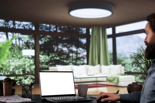 Influential CEO looks at laptop with white screen inside his posh villa
