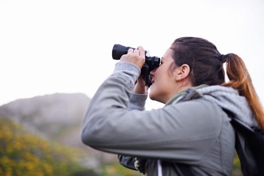 Woman, binoculars and hiking mountain for nature view on trekking path for explore, adventure or journey. Female person, backpacking and travel workout in wilderness fitness, vacation or environment