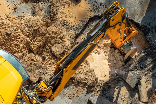 Digger digging asphalt to repair a water fault in a street