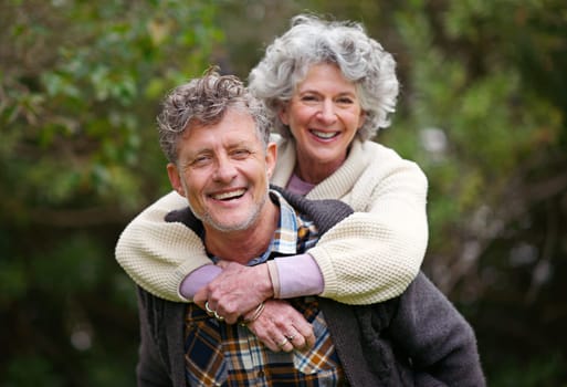 Portrait, retired people, smile on piggyback to relax in nature park as bonding together on holiday. Happy, older couple or love on fun vacation or walk as romantic date in retirement getaway