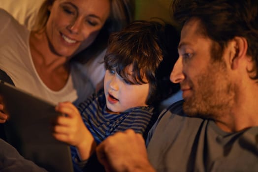 Bed, parents or kid with tablet for streaming, playing games or watching videos on movie website in home. Social media, child or happy mom with dad or technology to download on ebook online at night