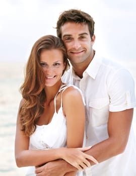 Happy couple, portrait and young love at beach, hug and travel on honeymoon adventure in sunshine. Man, woman and smile face for bonding in marriage, touch and together on ocean vacation in cape town