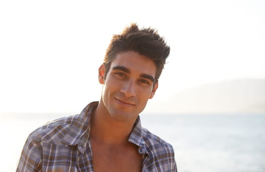 Man, sexy and travel with fashion, portrait and smile in landscape, confidence and pride. Male person, beach and hot by ocean, coast and tropical for summer, vacation and tourist in Cape Town.