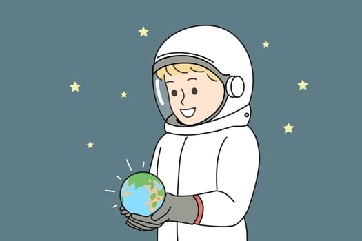 Boy dressed as astronaut is holding miniature planet earth, located in space with starry sky