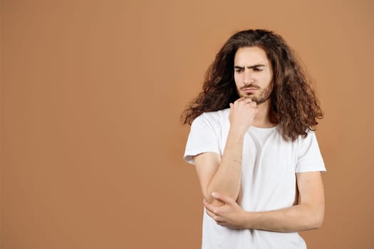 Portrait Of Depressed Hispanic Guy With Long Hair, Beige Background