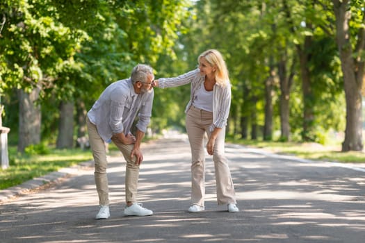 Mature Man Suffering Knee Injury While Walking In Park With Wife