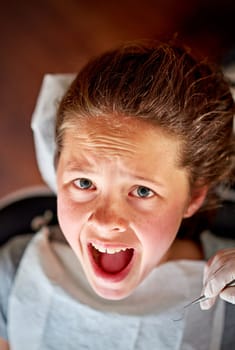 Scared, child and portrait at dentist for teeth, cleaning and fear of healthcare at clinic or hospital. Dental, care and kid afraid of tools in mouth and scream for help in medical appointment