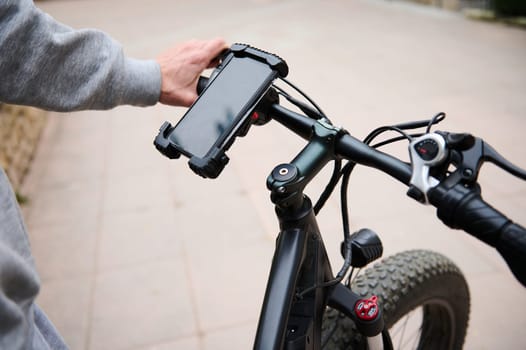 Cyclist sets up adjustments on mockup smartphone, renting electric bike using rental app. Bike sharing city service.