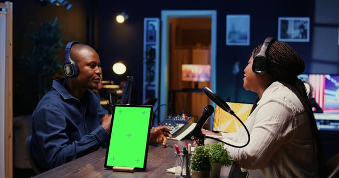 Chroma key device on table with man and woman sitting and discussing on podcast