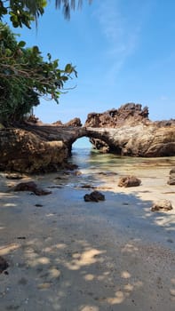 A massive rock formation dominates the sandy beach, standing tall against the backdrop of the serene coastline. Koh Libong Thailand