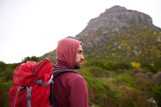 Man, hiking and mountain with backpack in nature, Germany trail on wildlife conservation. Active, male person on adventure for health and wellness, confident explorer on rocky terrain for sport.
