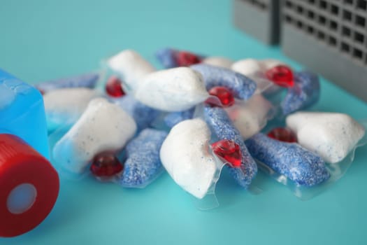 A stack of dishwasher tablets and a bottle of detergent on a blue background