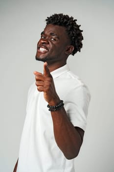 Young African Man Pointing at Something Against Gray Background close up