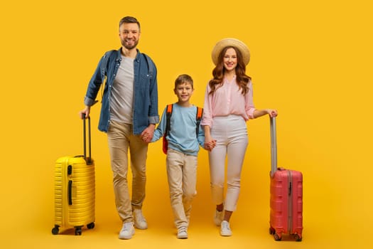 Family ready for vacation with luggage on yellow background