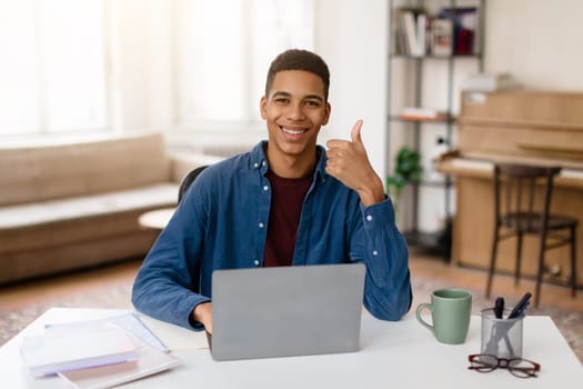 Happy black teen guy with laptop giving thumbs up