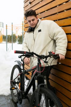 Cute young guy riding a bike around the city in winter