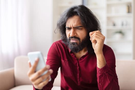 Man frustrated with smartphone at home, bad news