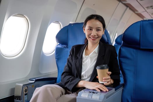 Young Asian woman sitting near the window on a business class airplane during a flight. Travel and business concept.
