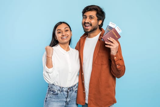 Excited couple with passports looking hopeful on blue