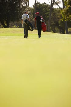Walking, people and men together on golf course with golfing bag for training, health and teamwork. Male friends, sports equipment and exercise for activity with sportswear, lawn and trees outdoor.