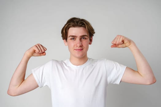 Young Man Flexing Muscles in Front of White Background