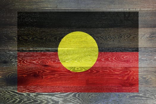 An Australia aboriginal flag on rustic old wood surface background black people red earth yellow sun