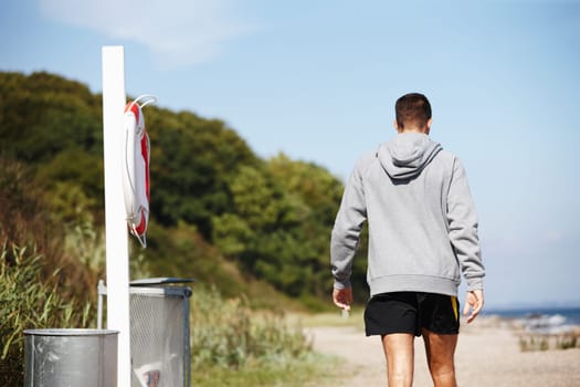 Rear view, man and jog for exercise on beach for fitness, workout and body health for physical training. Male runner or athlete and run for cardio, active strength or recreation in summer outside