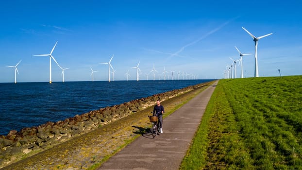 A man elegantly rides a electric bike down a scenic path with windmill turbines in the background