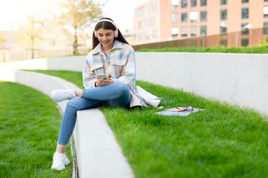 Young girl using smartphone and headphones in park