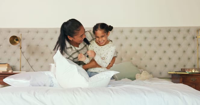 Happy, bedroom and mother tickling her child with love, care and playful expression at their home. Happiness, smile and young mom playing and bonding with her girl kid on a bed in their family house.