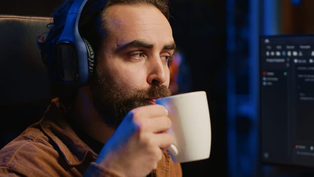 Developer listening music and drinking coffee while doing programming