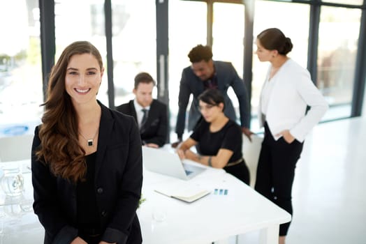 Professional, portrait of woman in office with confidence for leader or manager and team in meeting. Pride, smile and businesswoman with business people, collaboration and work on marketing strategy