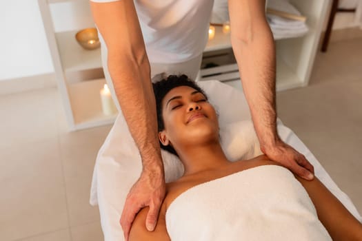 A tranquil image depicting a soothing shoulder massage for African American lady by a professional in a serene spa environment with a focus on alternative medicine