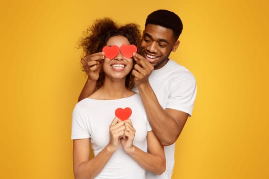 Young couple holding red love hearts over eyes