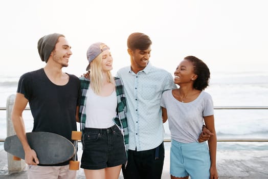 Group, friends and happy for hug on promenade by ocean for diversity, bonding or care on holiday. Men, women or gen z people with smile, embrace and outdoor on boardwalk for youth culture on vacation