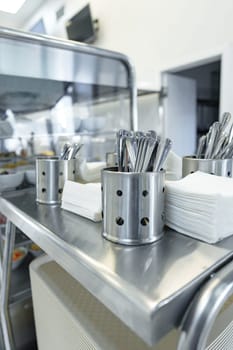 Stainless Steel Utensils Organized in Containers on a Service Cart in a Commercial Kitchen