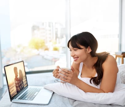 Woman, screen and laptop with smile in bed for streaming movies and series on website. Female person, home and happy with online entertainment or video in bedroom with coffee, relax and chill