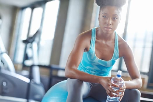 Relax, water and portrait of black woman on gym ball for fitness, workout pride and confidence in body care. Health, wellness and serious athlete girl with bottle on break at sports club for exercise.