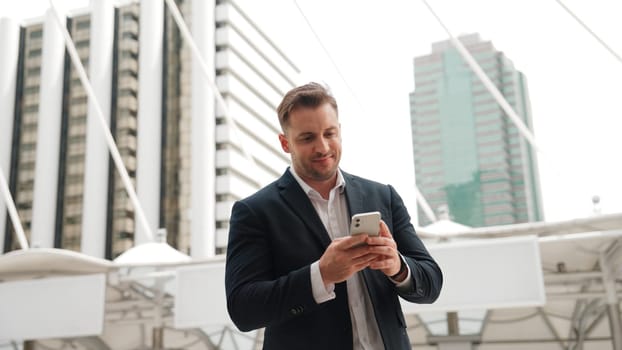 Caucasian business man checking mobile phone and looking report sales from marketing team while standing at urban city. Skilled manager working on mobile phone and looking at data analysis. Urbane.