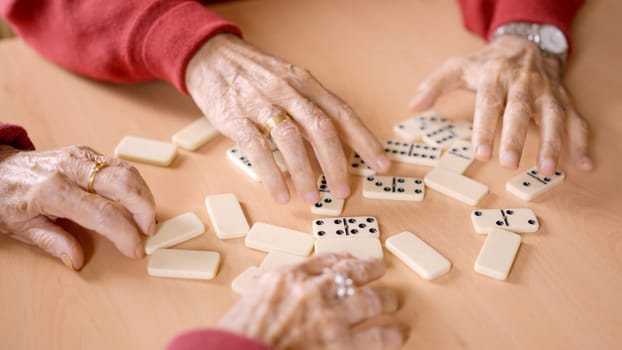 Close-up video of senior people sorting the domino tiles in a geriatric