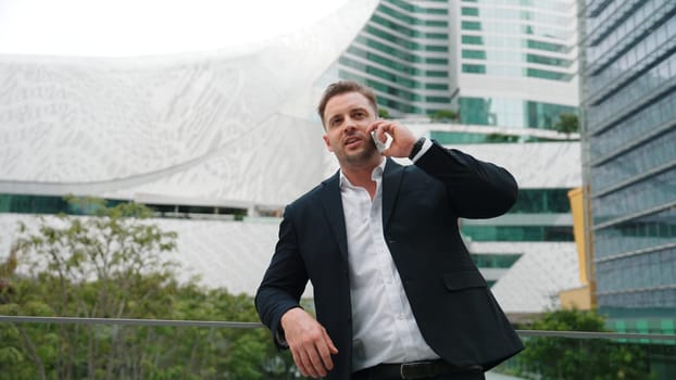 Smart caucasian businessman calling his colleague to plan financial strategy while standing at rooftop. Project manager using his mobile phone to communicate with marketing team. Lifestyle. Urbane.