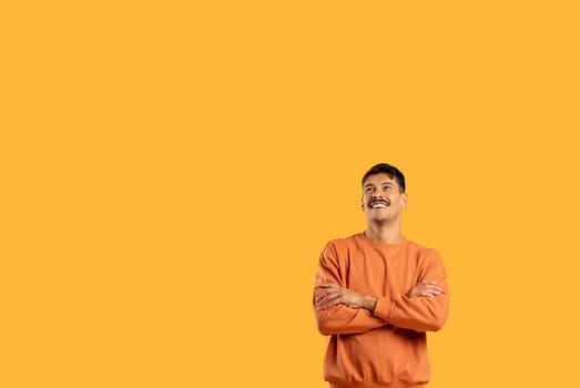 Smiling man in orange sweater on yellow