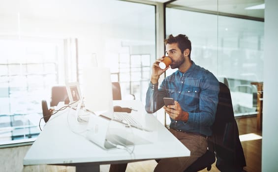 Businessman, coffee and cellphone at desk in office for networking communication and relax at work. Technology, male person and web development in workspace for online research and marketing company.